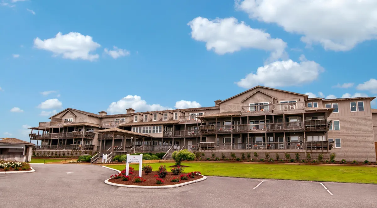 An exterior shot focused on the building's facade and the balconies, surrounded by a landscaped garden. The balconies are prominent, each offering private outdoor space with views of the ocean. The image conveys both the exclusivity and the inviting nature of the private balconies.