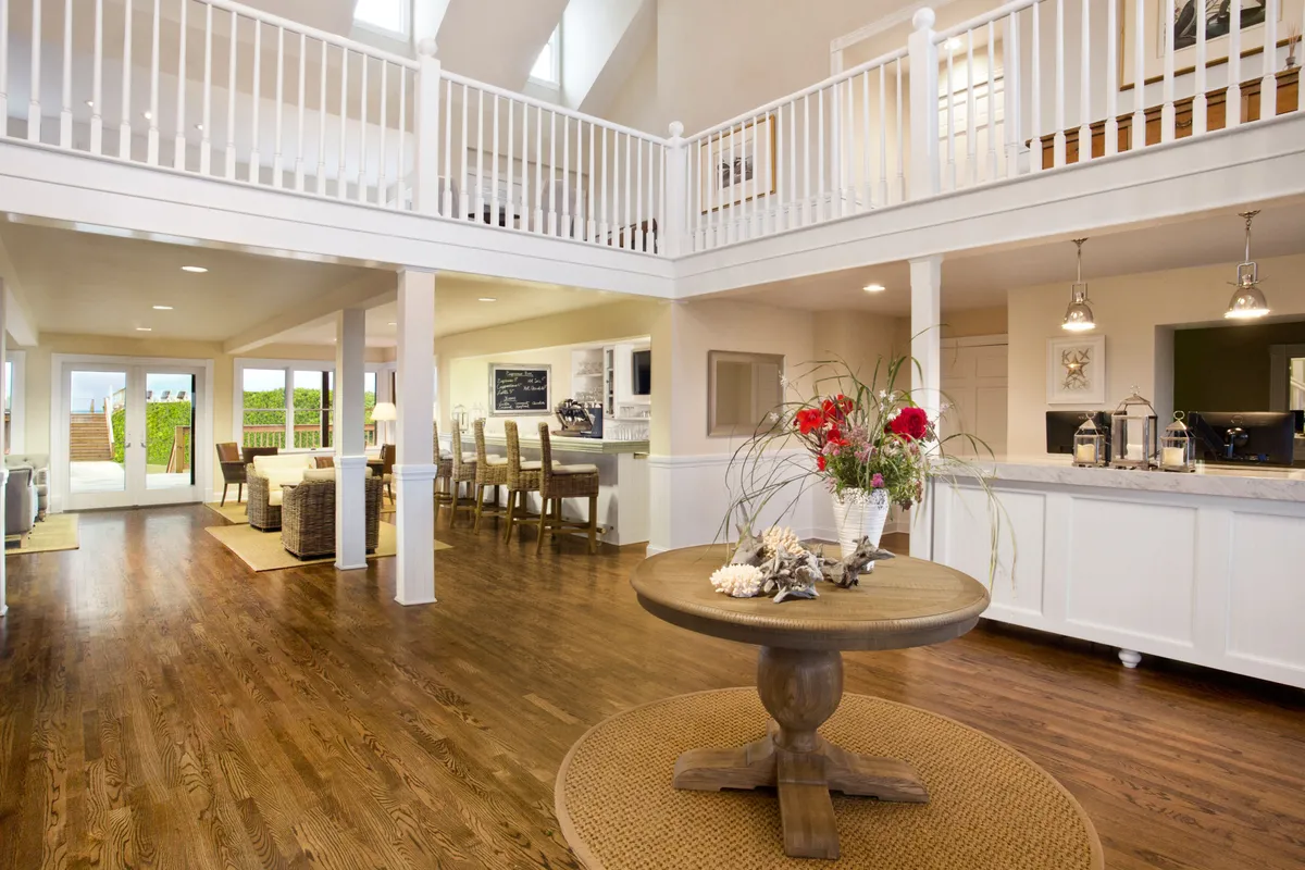 A spacious, airy interior with a central round table adorned with a floral arrangement, seamlessly connecting to an outdoor area. The open-plan design suggests a welcoming environment ideal for relaxing after outdoor adventures or gathering with loved ones, pets included.